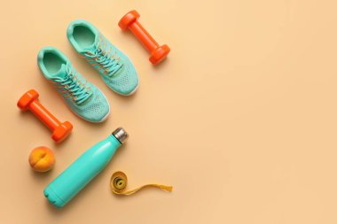 Ayakkabılı dambıllar, su şişesi ve renkli arka planda şerit.