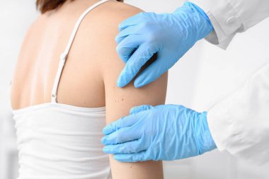 Dermatolog klinikteki hastayı muayene ediyor.