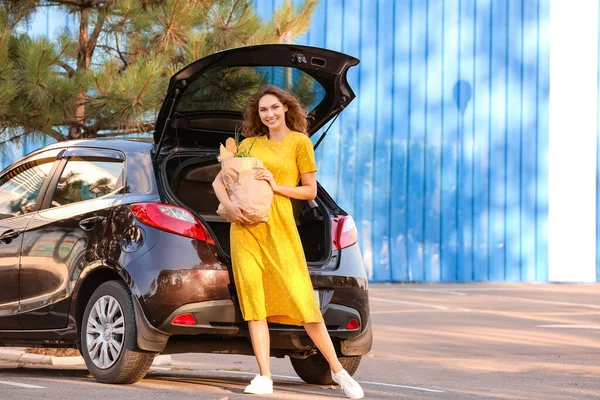 屋外で車の近くに食料品袋を持つ若い女性 — ストック写真