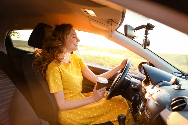 若い女性が車の中でコーヒーを飲む — ストック写真