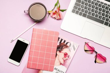 Cep telefonlu dizüstü bilgisayar, kırtasiye malzemesi ve renkli arka planda bir fincan kahve.