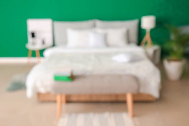 Modern odanın içinde büyük bir yatak ve bank, bulanık bir manzara.