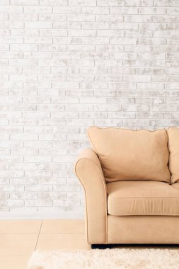 Odanın tuğla duvarının yanındaki yumuşak kanepe