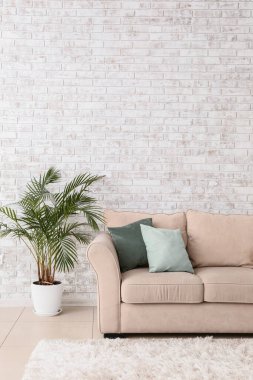 Odanın tuğla duvarının yanındaki yumuşak kanepe