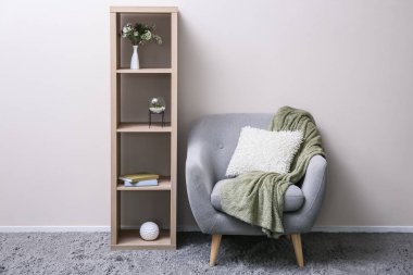 Odanın ışık duvarının yanında ahşap askı ve yumuşak koltuk