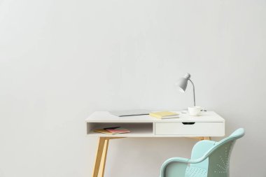 Işık duvarının yanında dizüstü bilgisayarı ve lambası olan işyeri