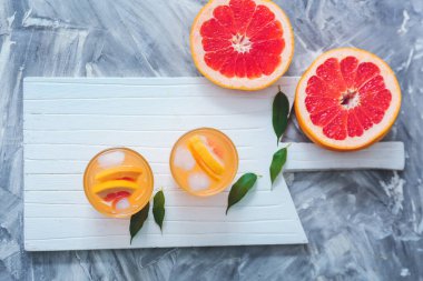 Gri arkaplanda bir bardak taze greyfurt suyu.