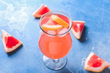 Arka planda bir bardak taze greyfurt suyu.