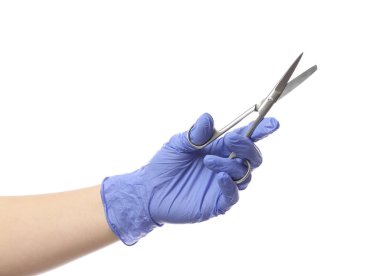 Kadın eli eldivende, beyaz arka planda cerrah aleti var.