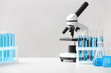 Modern mikroskop ve cam eşyalar laboratuardaki masada.