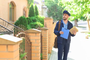 Dışarıda mektupları olan yakışıklı bir postacı.