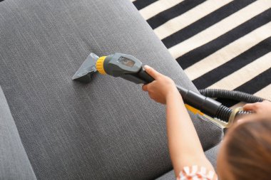 Kadın evdeki kanepenin pisliğini temizliyor.