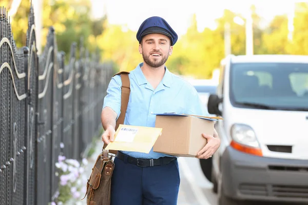 一个年轻英俊的邮递员 带着包裹在外面 — 图库照片