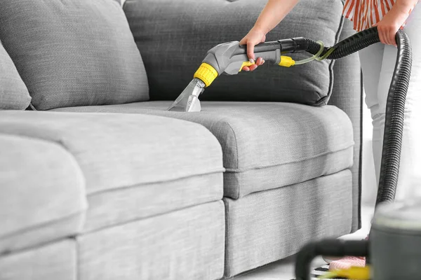 Woman removing dirt from sofa at home