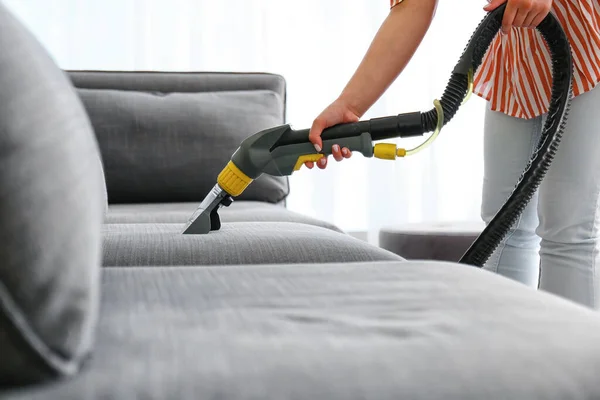 Woman removing dirt from sofa at home