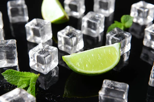 Ice cubes, lime and mint on dark background