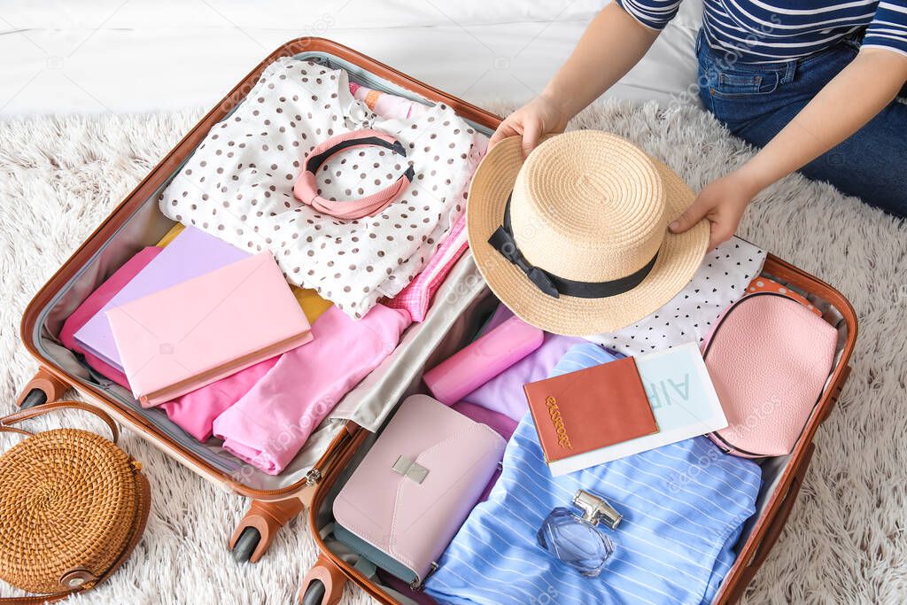 Woman packing suitcase for journey at home