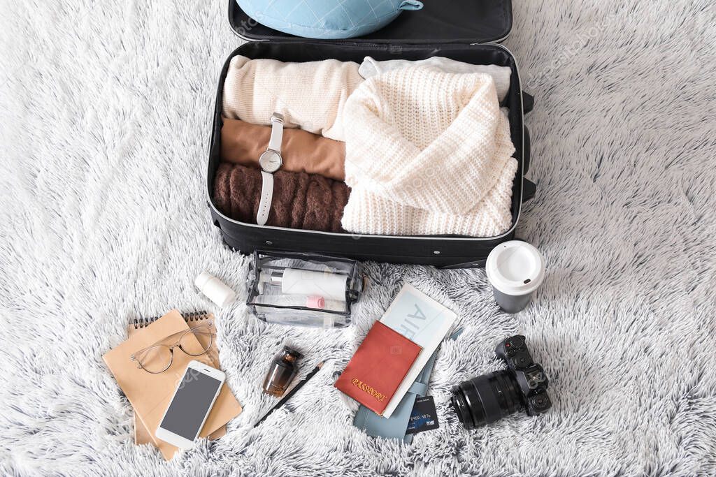 Suitcase with female clothes and accessories on bed