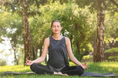 Genç hamile kadın dışarıda yoga yapıyor.