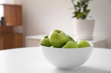 Yemek odasındaki masada taze elmalarla kase.