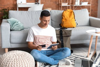 Tabletli bir adam evde online bilet ayırtıyor.