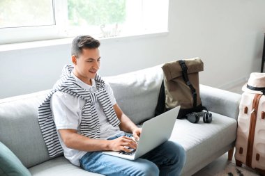 Bilgisayarlı bir adam evde online bilet ayırtıyor.