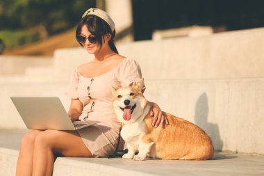 Şirin Corgi köpeği olan bir kadın dışarıda yürüyor.