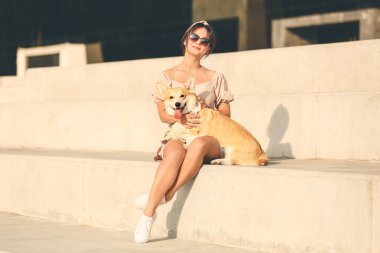 Şirin Corgi köpeği olan bir kadın dışarıda yürüyor.