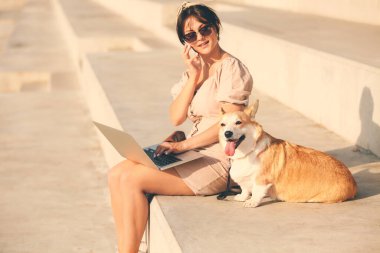 Şirin Corgi köpeği olan bir kadın dışarıda yürüyor.
