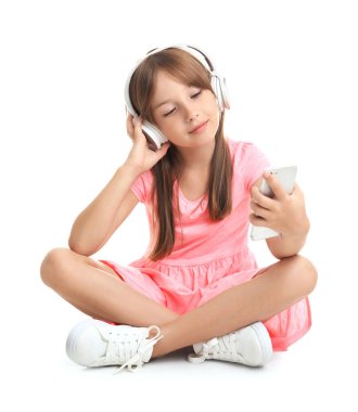 Küçük kız beyaz arka planda müzik dinliyor.