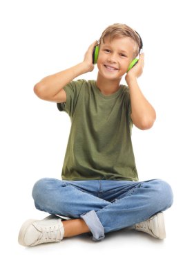 Küçük çocuk beyaz arka planda müzik dinliyor.