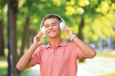 Genç çocuk parkta müzik dinliyor.