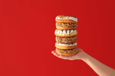 Renkli arkaplanda lezzetli donutlar olan bir el.