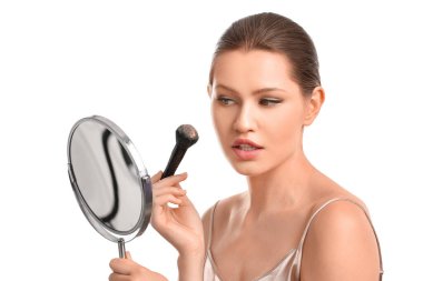 Güzel genç bir kadın beyaz arka plana makyaj yapıyor.