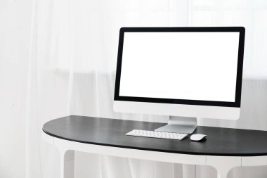Pencerenin yanındaki masadaki modern PC monitörü