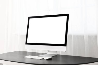 Pencerenin yanındaki masadaki modern PC monitörü