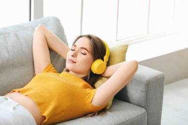Uykulu genç kadın evde müzik dinliyor.