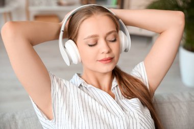 Uykulu genç kadın evde müzik dinliyor.