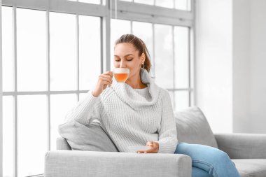 Güzel genç bayan evde çay içiyor.