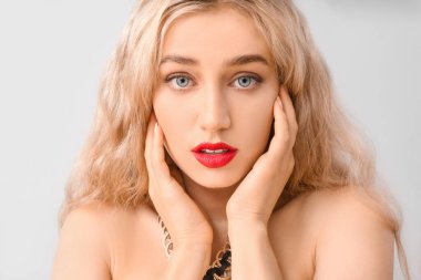 Gri arkaplanda parlak ruj izi olan güzel bir genç kadın.