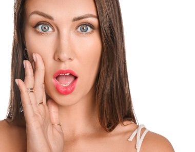 Beyaz arka planda güzel makyajlı, şaşırmış genç bir kadın.