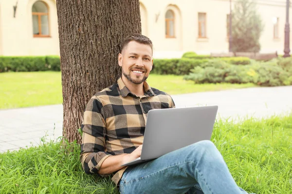 Handsome man with laptop relaxing in park