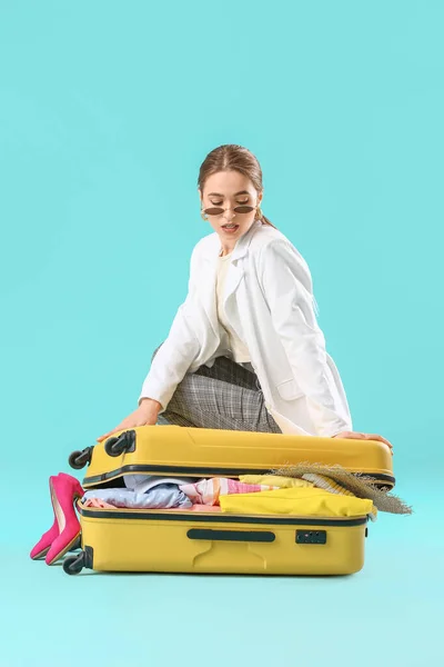 Young Woman Trying Close Suitcase Lot Things Color Background Travel — Stock Photo, Image