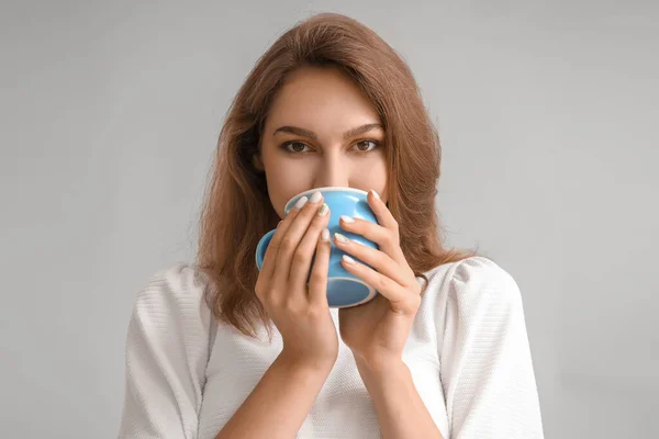 漂亮的年轻女子 有一杯灰色背景的茶 — 图库照片