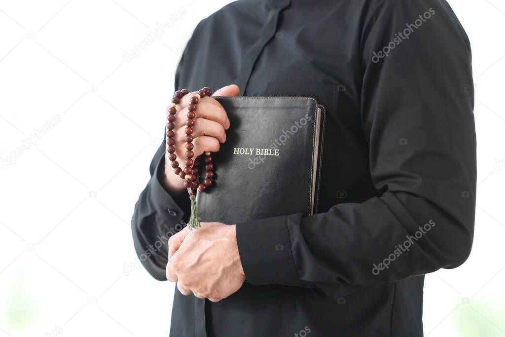 Male priest with Bible at home