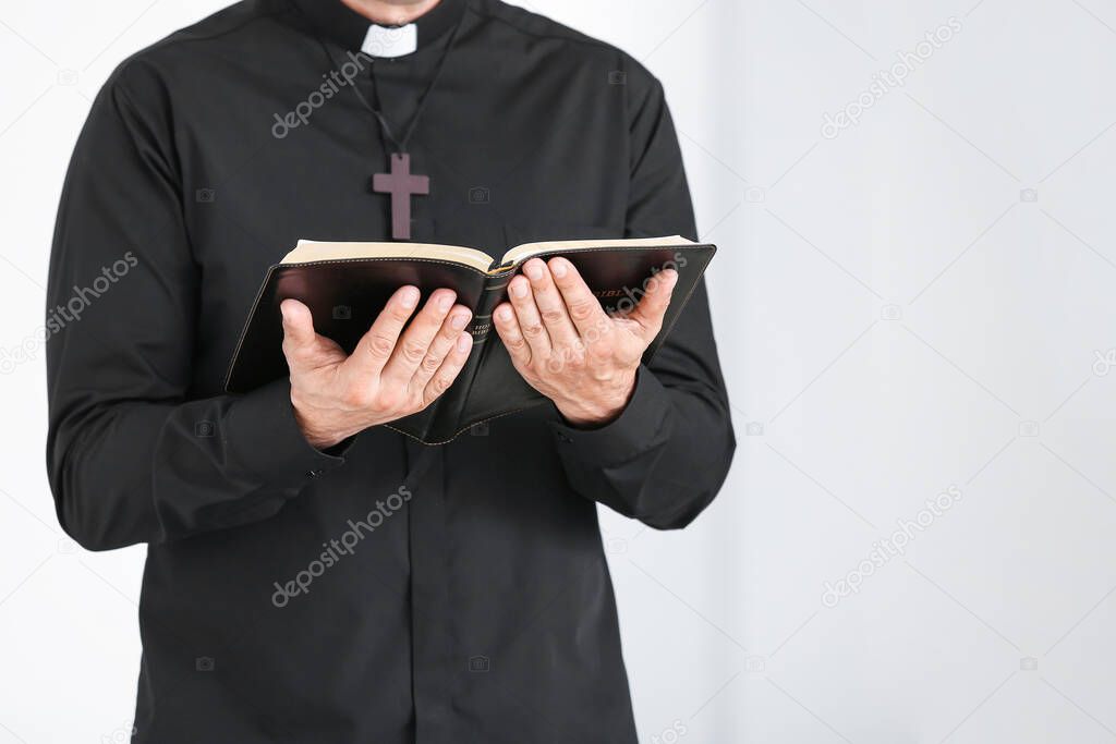 Male priest with Bible at home