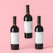 Láhve vína s prázdnými etiketami na barevném pozadí. Mockup pro design