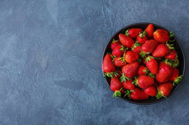 Koyu arka planda taze olgun çilekli kase.