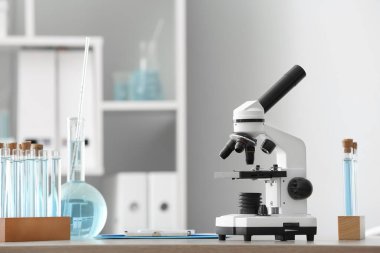 Laboratuvardaki masada mikroskop ve cam eşyalar.