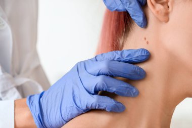Dermatolog klinikteki hastayı muayene ediyor.